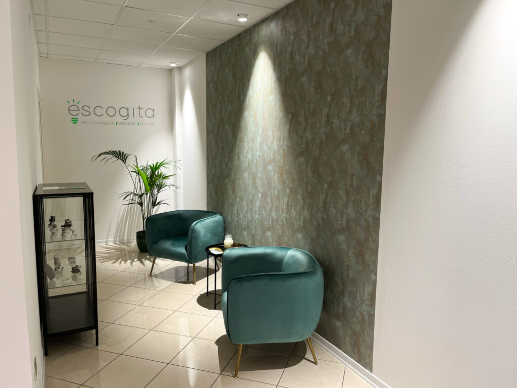 Zona accoglienza dell’ufficio Escogita con poltrone verdi, pareti moderne e piante ornamentali
