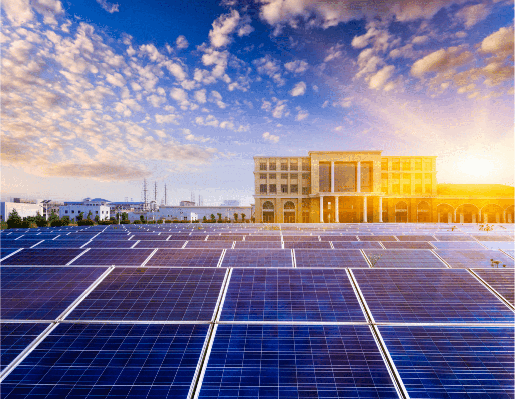 Campo fotovoltaico installato davanti a un edificio pubblico al tramonto
